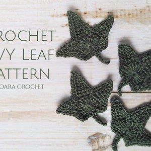 May include: Four crocheted green ivy leaves on a white wooden background. The text "CROCHET IVY LEAF PATTERN MOARA CROCHET" is visible in the top left corner of the image.