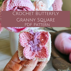 Könnte beinhalten: Ein Häkel-Oma-Quadrat mit einem Schmetterlingsmuster in Rosa, Lila und Weiß. Das Quadrat wird in einer Hand gehalten. Der Text "CROCHET BUTTERFLY GRANNY SQUARE PDF PATTERN" wird über dem Quadrat angezeigt.