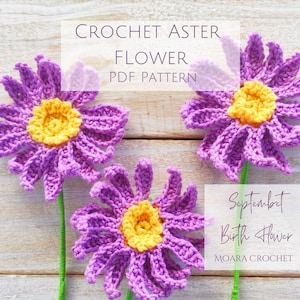 以下が含まれることがあります： 紫色の花びらと黄色の中心を持つ、手作りのかぎ針編みの3つのアスターの花。花には緑色の茎があります。画像には「CROCHET ASTER FLOWER PDF PATTERN」と「September Birth Flower」と書かれています。