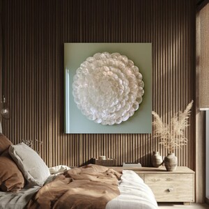 Puede incluir: Una pieza de arte mural cuadrada que presenta una disposición circular de discos blancos translúcidos superpuestos centrados sobre un fondo verde pálido, montada en una pared de listones verticales marrón oscuro sobre muebles de dormitorio.