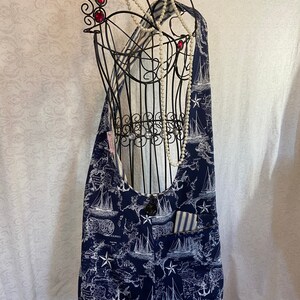 May include: A navy blue canvas tote bag with a white nautical map print featuring ships, anchors, and stars. The bag has a large pocket on the front with a striped fabric lining.
