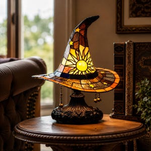 Peut inclure: Une lampe de table en vitrail en forme de chapeau de sorcière pointu. La lampe présente un motif de soleil jaune vif sur le devant, entouré de panneaux de verre orange, marron et bleu avec de petites étoiles jaunes et des chaînes en métal.