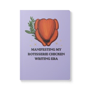 May include: A light purple notebook featuring a central illustration of a roasted chicken with green herbs. Below the chicken are small gold star accents and the text "MANIFESTING MY ROTISSERIE CHICKEN WRITING ERA" in dark brown capital letters.