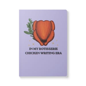 May include: A light purple notebook featuring a central illustration of a roasted chicken with a sprig of green herbs. Below the chicken are small gold star accents and the text "IN MY ROTISSERIE CHICKEN WRITING ERA" printed in dark brown capital letters.