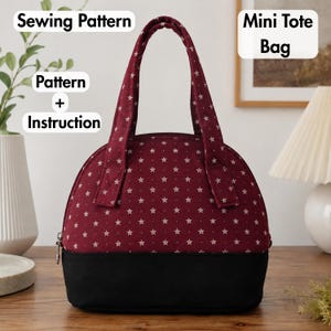 May include: A mini tote bag sewing pattern and instruction set. The bag features a deep red fabric with a white star print on the upper portion and a solid black fabric base. It has two matching red star-print handles and a zipper closure.