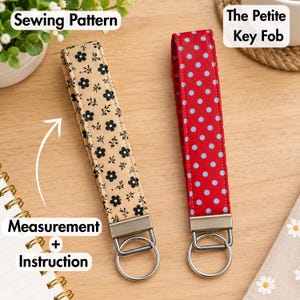May include: Two fabric key fobs with metal hardware and rings. One key fob is beige with a black floral pattern, and the other is red with light blue polka dots. Text on the image reads Sewing Pattern, The Petite Key Fob, and Measurement + Instruction.