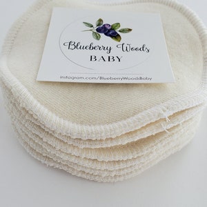 May include: A stack of 10 off-white reusable makeup remover pads with a white label that says "Blueberry Woods Baby" and includes a website address.