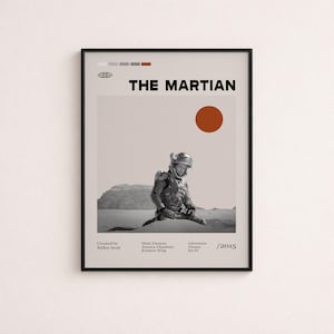 May include: A framed movie poster for The Martian featuring a black and white image of an astronaut in a desert landscape. The poster includes the title, a red circle representing the sun, and text listing the director, cast, genre, and year 2015.