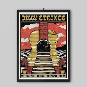 Op de afbeelding: Een ingelijste concertposter voor Billy Strings met het silhouet van een grote gele gitaar tegen een rode lucht met wolken. Een bakstenen schoorsteen rijst op uit de gitaar, die een ronde opening heeft met een nachtelijke hemel en een maan.