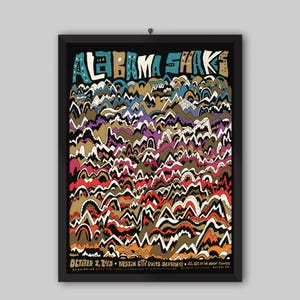 Può includere: Un poster da concerto incorniciato per Alabama Shakes con un motivo denso e colorato di cime montuose stilizzate in tonalità di rosso, arancione, marrone chiaro, viola e blu su sfondo nero. Il testo riporta Alabama Shakes e October 2, 2015.
