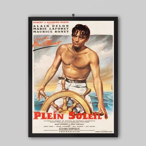 Pode incluir: Um cartaz de filme vintage emoldurado de Plein Soleil apresentando uma pessoa sem camisa com cabelo escuro em um leme de navio de madeira. O fundo mostra um mar azul e um céu nublado. O texto inclui nomes como Alain Delon e Marie Laforet.