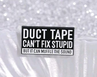 May include: A rectangular black and white pin with the text "DUCT TAPE CAN'T FIX STUPID BUT IT CAN MUFFLE THE SOUND". The pin is set against a sparkly, glittery background.