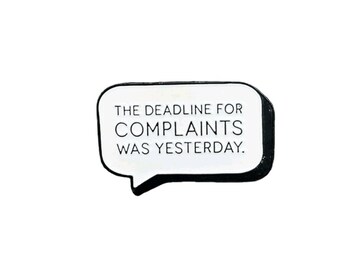 May include: A white speech bubble-shaped pin with a black border. The text inside reads: "THE DEADLINE FOR COMPLAINTS WAS YESTERDAY."