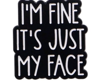 May include: Black enamel pin with white text that reads "I'm fine it's just my face".
