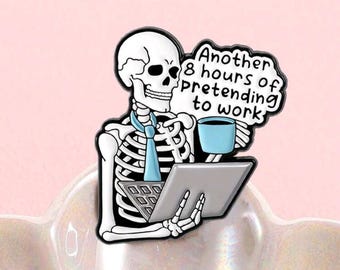 May include: A novelty pin featuring a skeleton wearing a blue tie, holding a tablet and a blue coffee cup. The pin has the text "Another 8 hours of pretending to work" in a speech bubble. The pin is set against a pink background.