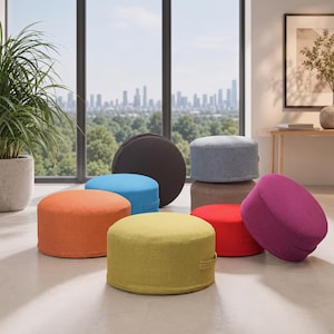 May include: A collection of round, fabric-covered floor cushions in various solid colours including orange, yellow, blue, dark brown, light grey, tan, red, and magenta. Each cushion features a small side handle for easy carrying and placement.
