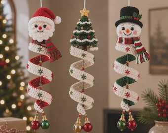 May include: Three hanging crochet ornaments featuring a Santa Claus, a Christmas tree, and a snowman. Each figure has a long, spiraling white ribbon body decorated with small embroidered snowflakes, ending in two shiny red and green spherical bells.