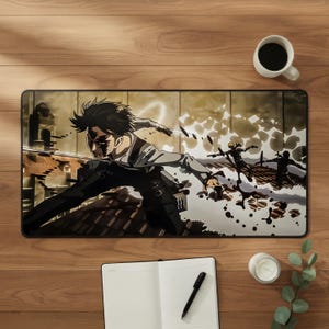 May include: A rectangular desk mat featuring a dynamic anime-style illustration of a character with dark hair in a combat pose, wielding blades while leaping over rooftops. The scene includes motion effects, debris, and two smaller figures in the background.