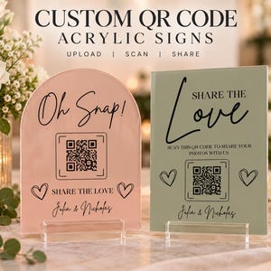 May include: Two custom acrylic signs with QR codes. The left sign is arched and blush pink, reading "Oh Snap!", "SHARE THE LOVE", and "Julia & Nicholas". The right sign is rectangular and sage green, reading "SHARE THE LOVE" and "Julia & Nicholas".