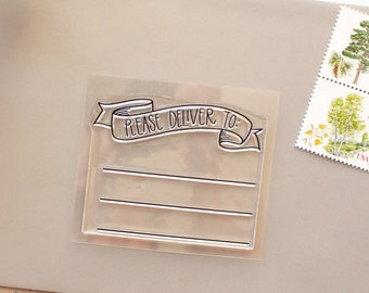 May include: A clear rubber stamp with a banner that reads "Please Deliver To" and three blank lines for writing. The stamp is on a beige envelope with a brown paper background.