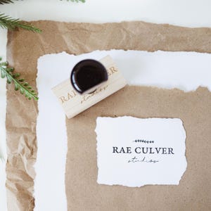 May include: A wooden stamp with the text "Rae Culver studios" in black ink on a brown paper background.