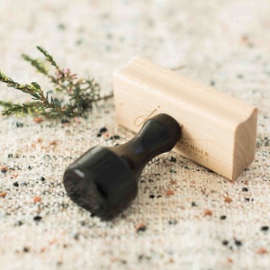 May include: A wooden stamp with a black handle. The stamp is engraved with the text "MONGER & COMPANY".