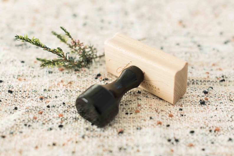 May include: A wooden stamp with a black handle. The stamp is engraved with the text "MONGER & COMPANY".