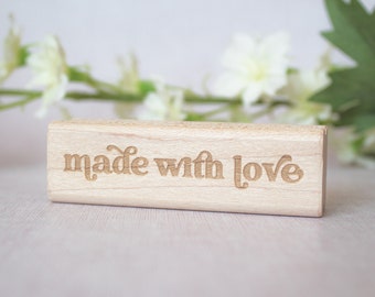 Könnte beinhalten: Ein Holzschild mit dem Text "made with love" in einer dekorativen Schriftart.