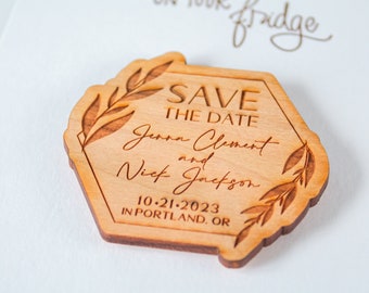 May include: Wooden save the date magnet with a hexagonal shape and a floral design. The text reads "Save the Date, Jenna Clement and Nick Jackson, 10-21-2023, in Portland, OR."