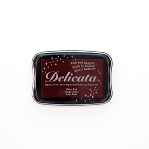 May include: A red ink pad with the text "Delicata" and "Rich and Radiant" in white. The ink pad is labeled "Ruby Red", "Rouge Rubis", and "Rojo Rub&iacute;".