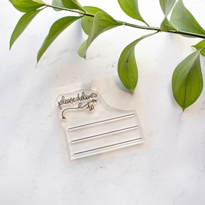 May include: Clear acrylic stamp with the text "please deliver to" and three blank lines for writing an address.