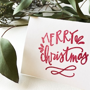 May include: A white card with the words "Merry Christmas" written in red cursive script.