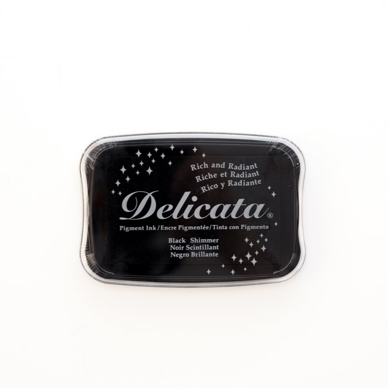 May include: A black ink pad with the text "Delicata" in a silver script font. The ink pad is labeled "Rich and Radiant" and "Black Shimmer".