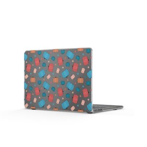 May include: A laptop computer featuring a dark gray hard shell case decorated with a repeating pattern of small pumpkins in shades of blue, pink, and orange, interspersed with tiny four-pointed star shapes across the entire surface.