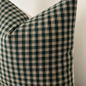 May include: A green and white plaid pillow cover. The pillow cover has a square pattern with a dark green background and white lines.