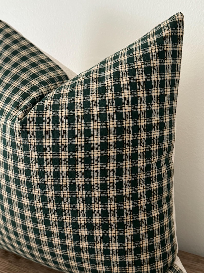May include: A green and white plaid pillow cover. The pillow cover has a square pattern with a dark green background and white lines.