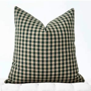 May include: A green and cream plaid throw pillow with a square shape.