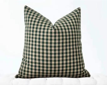 May include: A green and cream plaid throw pillow with a square shape.