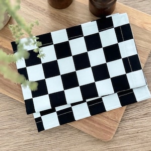 May include: A black and white checkered fabric napkin, folded in half, on a wooden surface.