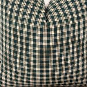 May include: A green and cream plaid pillow cover. The pillow cover is made of a soft, woven fabric and has a subtle sheen.