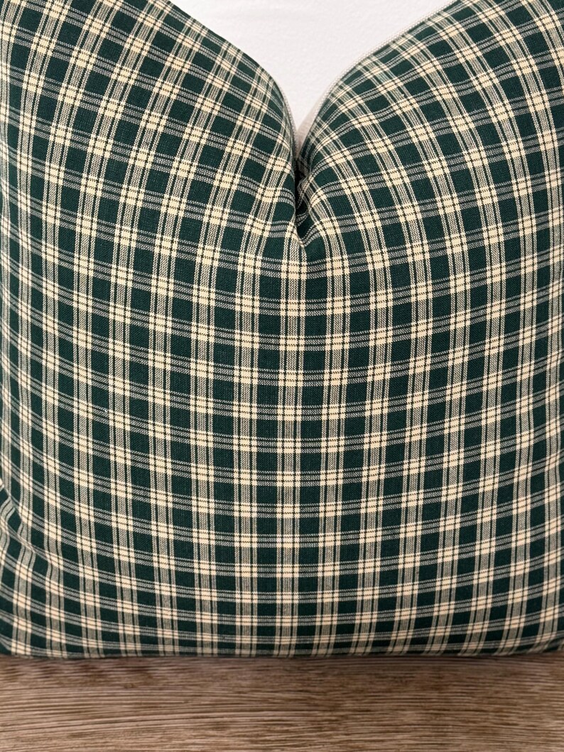 May include: A green and cream plaid pillow cover. The pillow cover is made of a soft, woven fabric and has a subtle sheen.