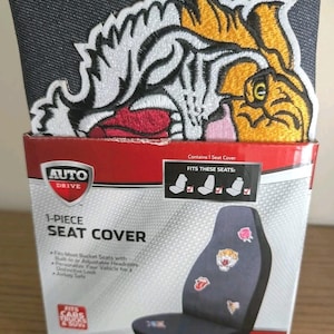 May include: An Auto Drive 1-piece seat cover in a box. The packaging features a large embroidered tiger patch in yellow, white, and black. The box displays text including 1-PIECE SEAT COVER, FITS THESE SEATS, and FITS CARS TRUCKS & SUVS.