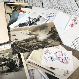May include: A stack of vintage postcards and photographs, including a black and white photo of a pier and a postcard with a pink teddy bear and the text "A Little Gift for a Baby Boy".