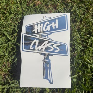 May include: A rectangular white decal featuring a graphic of two stacked street signs on a post. The signs are blue with a metallic, reflective finish and white text that reads HIGH on the top sign and CLASS on the bottom sign.