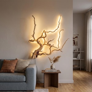 Puede incluir: Una lámpara de pared fabricada con una rama de madera flotante natural de color claro. La estructura orgánica de madera nudosa cuenta con iluminación LED cálida integrada que sigue el contorno de las ramas, emitiendo un brillo suave.