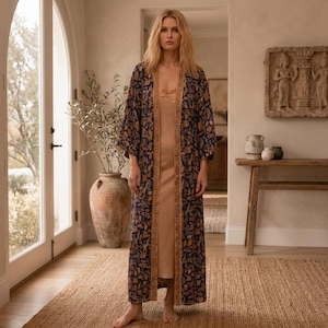 May include: A floor-length navy blue kimono robe featuring a repeating tan floral pattern and a wide, solid tan border along the front opening. The garment is worn over a simple, sleeveless, solid tan slip dress that reaches the ankles.