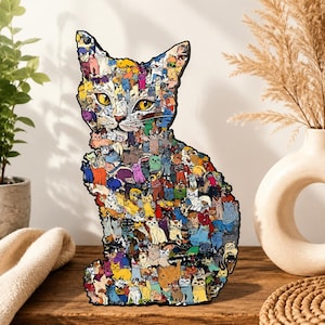 May include: A decorative cat-shaped wooden cutout featuring a collage of numerous small, colourful cat illustrations in various poses and shades, including yellow, blue, orange, and purple, with a prominent pair of large, bright yellow cat eyes.
