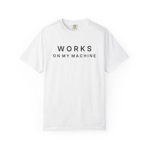 May include: A white short-sleeved t-shirt featuring the black text "WORKS ON MY MACHINE" printed in a clean, sans-serif font across the chest. The garment has a classic crew neckline and a standard fit, showcasing a simple and direct design.