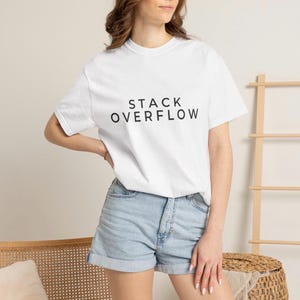 May include: A white short-sleeved t-shirt featuring the black text STACK OVERFLOW printed in the centre of the chest. The shirt has a crew neckline and is paired with light blue denim shorts that have a cuffed hem at the bottom of the legs.