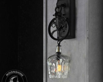 Industrial Pulley Wheel Wall Sconce With Recycled Crown Royal Glass Bottle Lamp Shade and Vintage Style Edison Bulb